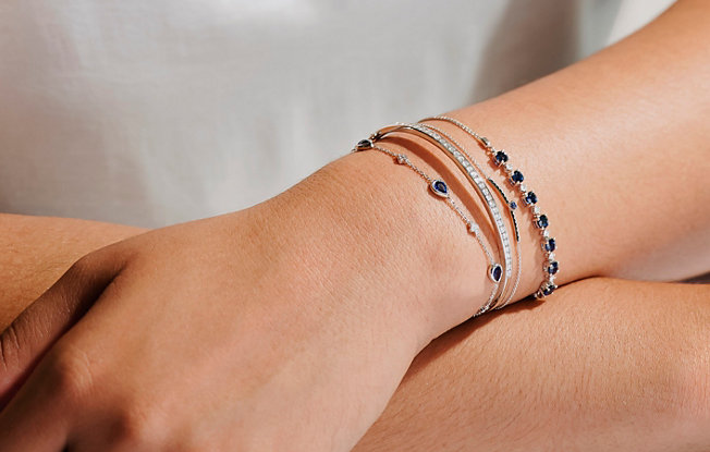 A woman wearing several delicate bracelets with gemstones and diamonds