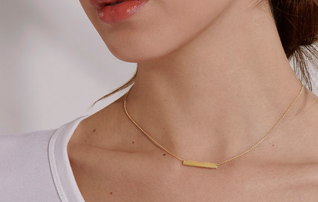 A woman wearing an engravable bar necklace