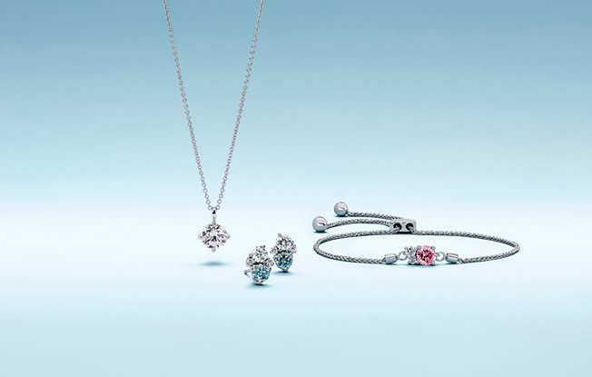 A diamond pendent, blue diamond earrings and a pink diamond bracelet made with lightbox lab grown diamonds on a blue background