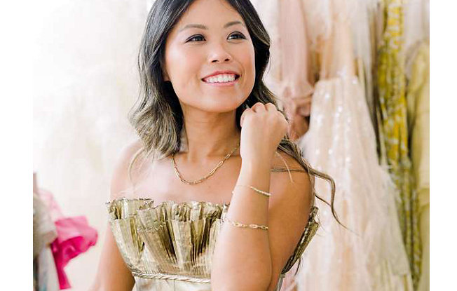 Woman in a gold party dress and gold chain showing her bracelets
