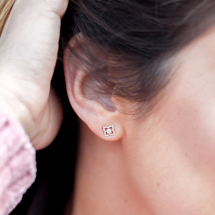 Close up of woman's ear lobe, she is wearing a diamond and gold earring 