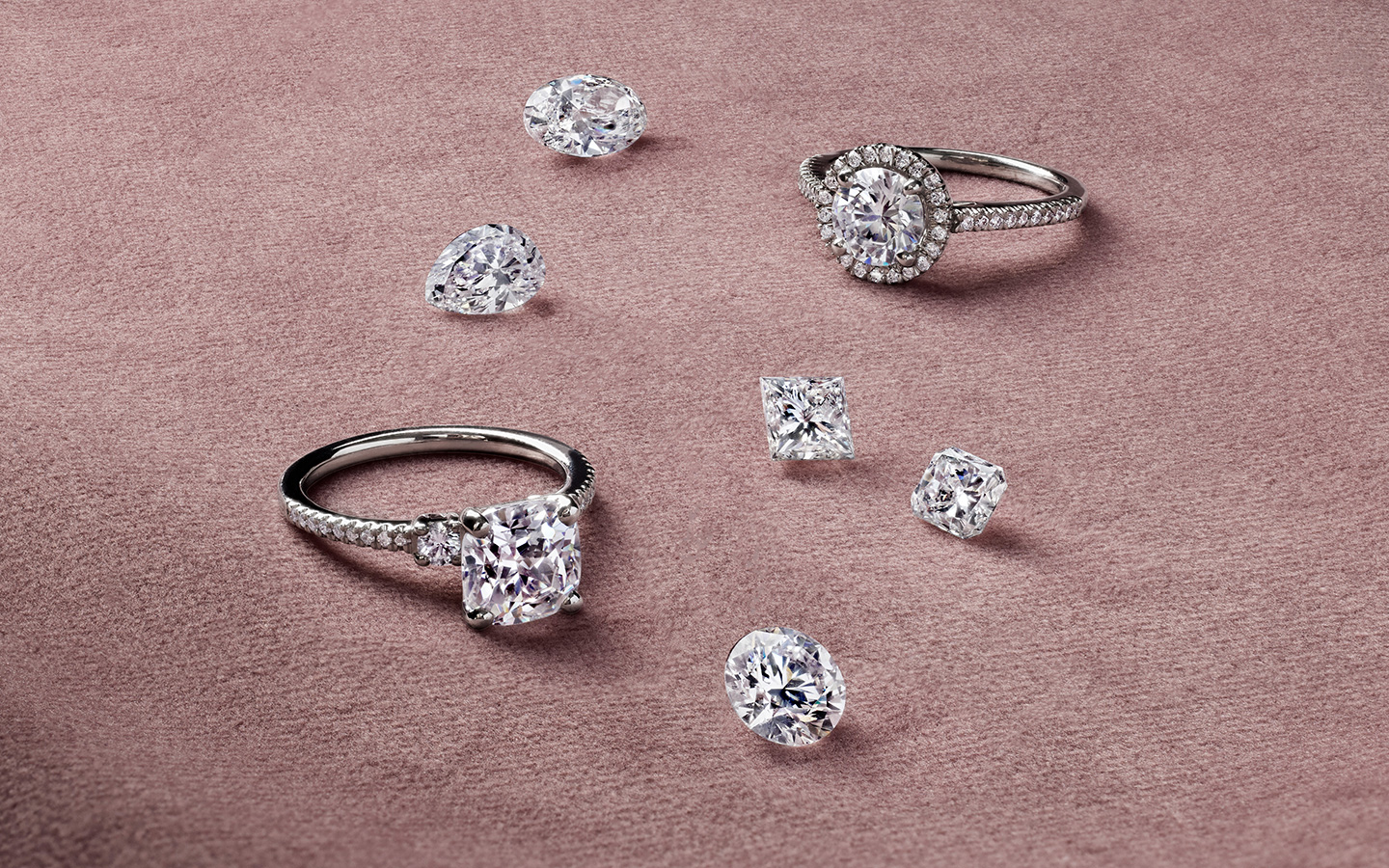 Two diamond engagement rings with loose diamonds nearby, image features both natural and lab made diamonds.