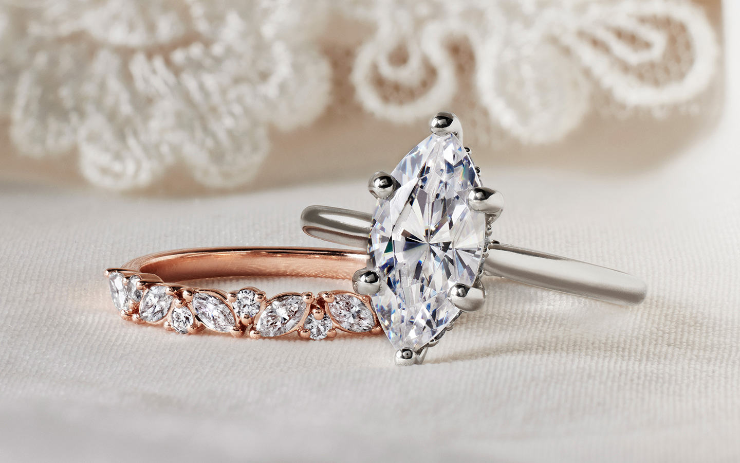 Marquise diamond engagement ring in white gold next to a rose gold ring.