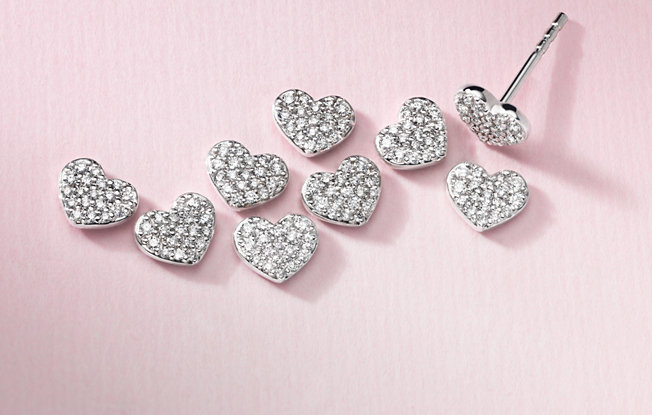 9 diamond heart shaped earrings on a pink background