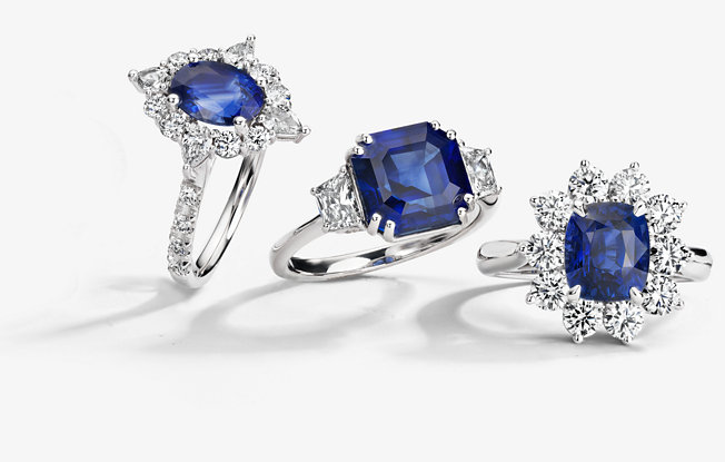 3 gemstone engagement rings of different styles on a gray background