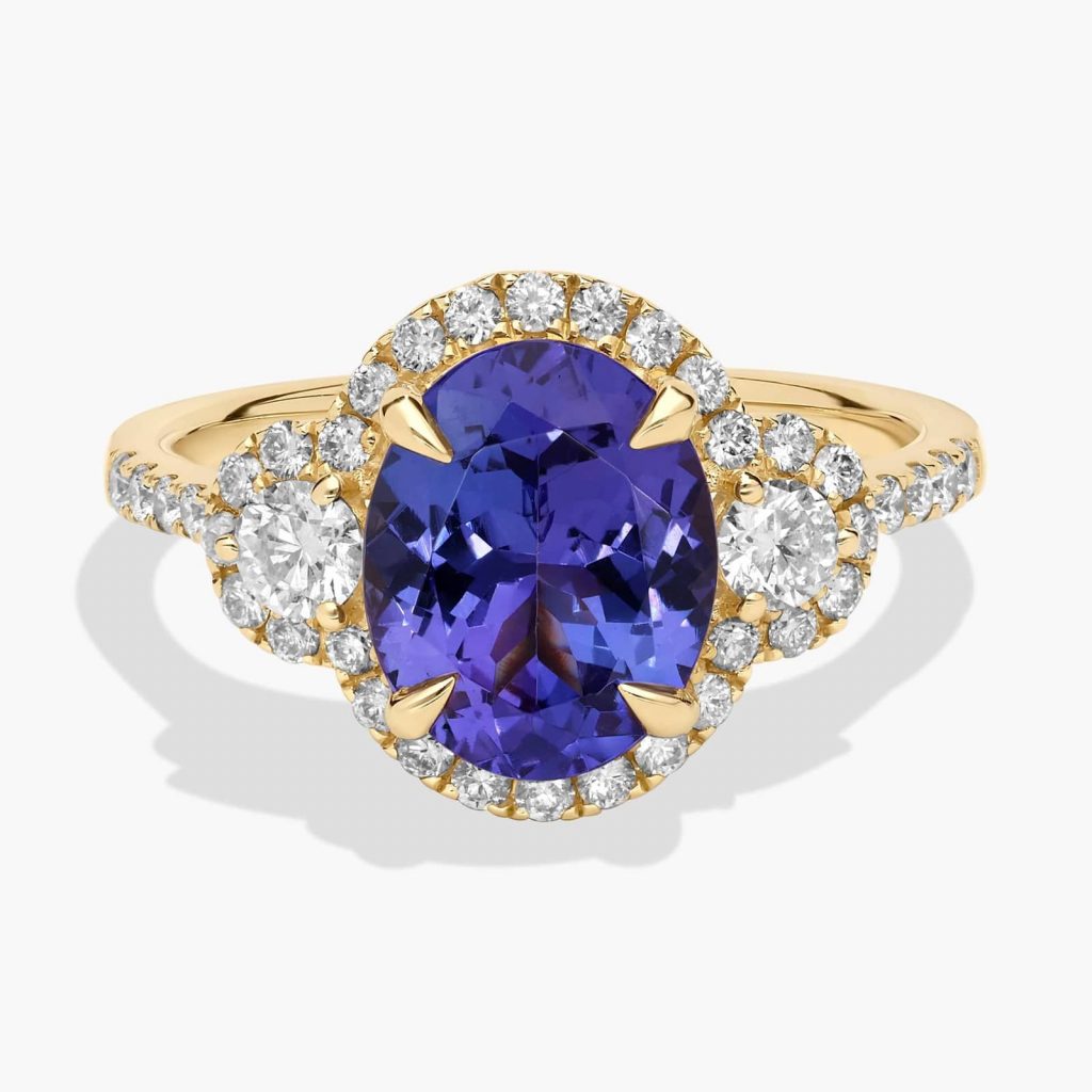 Violet-blue tanzanite wrapped in white stones on a gold band, a striking choice for alternative stones for engagement rings