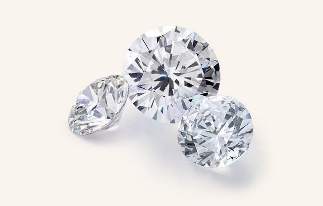 Three loose round diamonds on a cream colored background