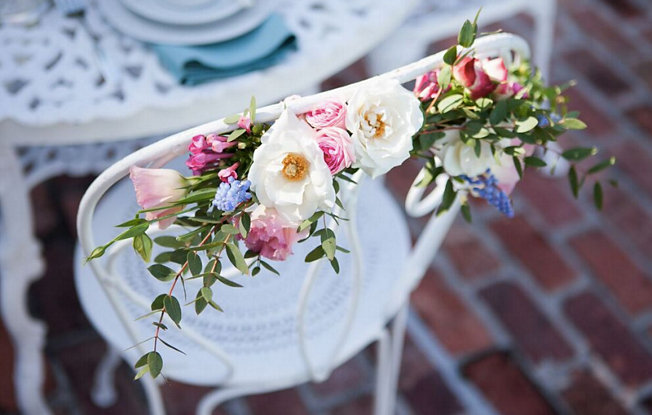 Pink and white flowers with green leaves on a white iron chair