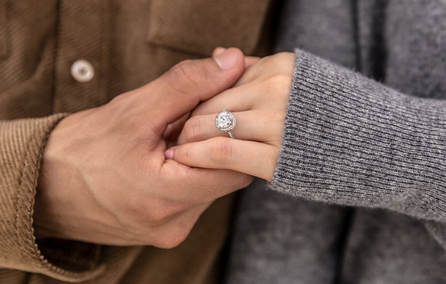 holding hands, womans hand wearing halo diamond engagement ring
