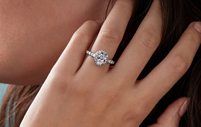 A round cut platinum engagement ring with diamonds on a woman's hand