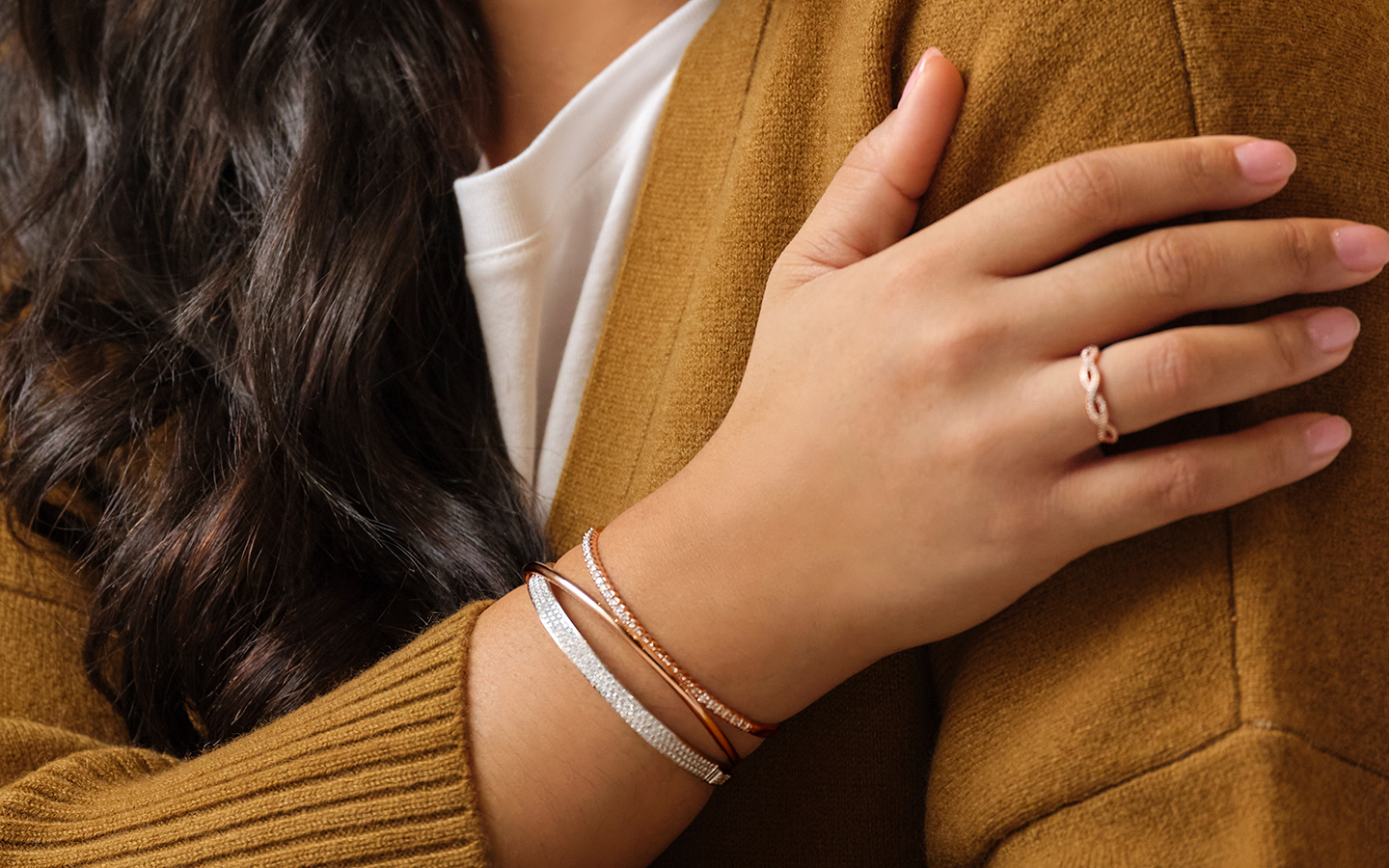 Woman wearing bracelets including a bangle and tennis bracelet.