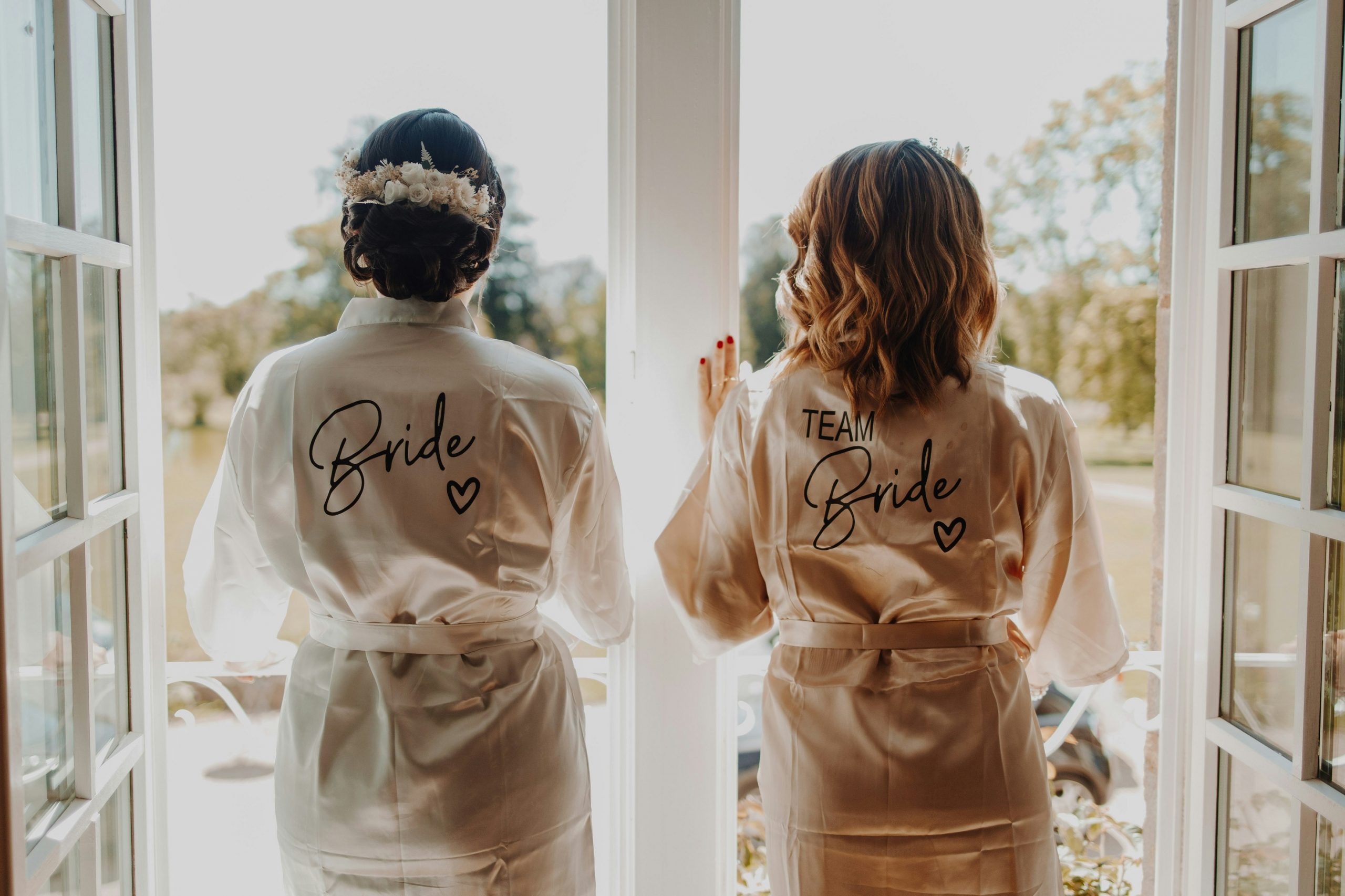 Bride and bridesmaid getting ready in robes on the wedding day