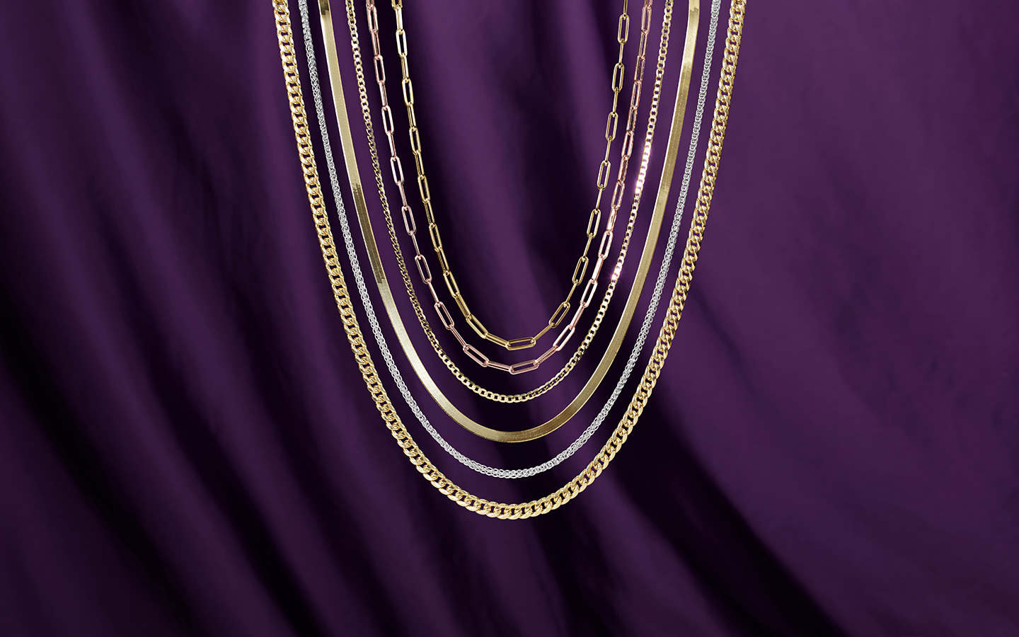 Six yellow and white gold necklaces including a Cuban chain, a herringbone necklace and paperclip necklaces. 