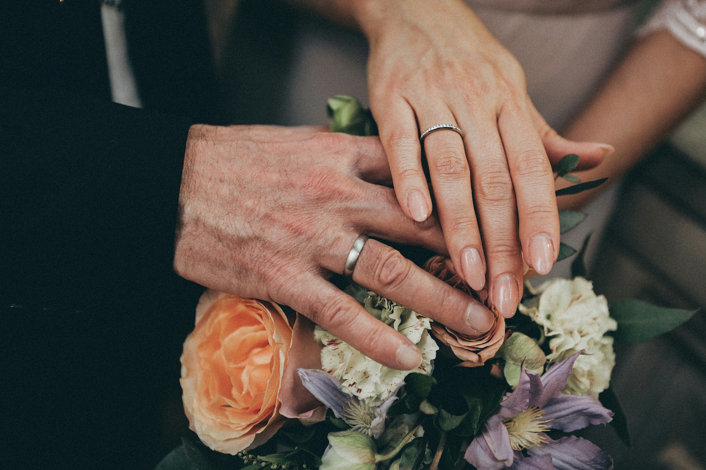 Photo of a couple’s hands on a commitment ceremony bouquet.