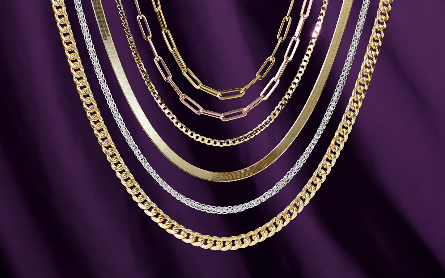 Six necklaces including a herringbone chain, paperclip necklaces and Cuban chains in gold.