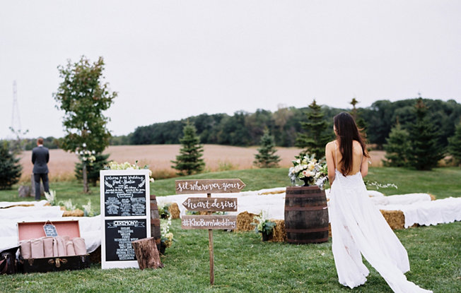 An outdoor wedding scene with a woman in a wedding dress and a man in a suit looking out toward the distance