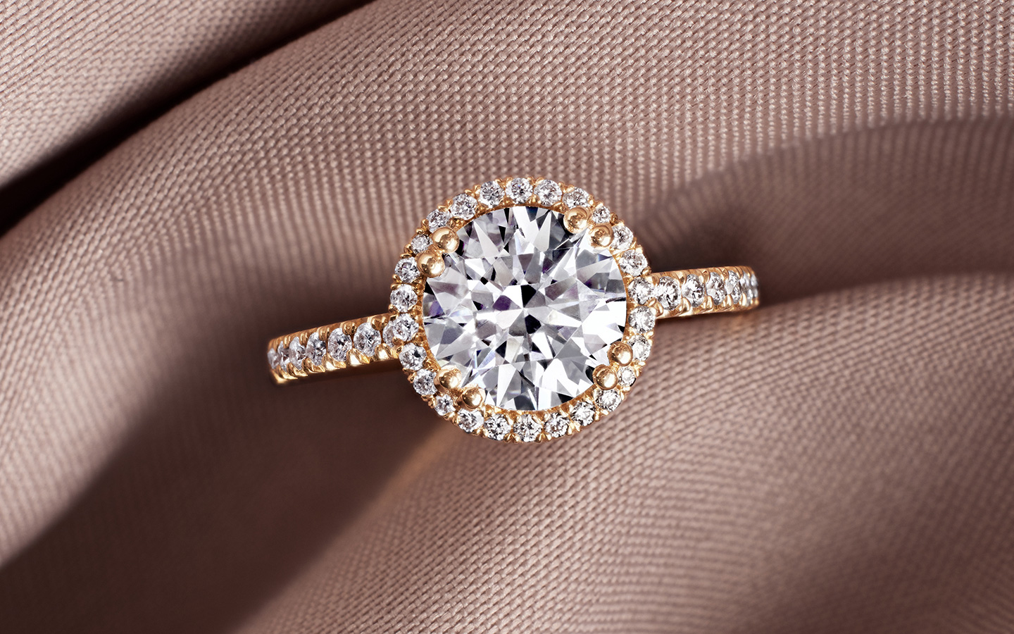 Custom engagement ring in gold with halo diamonds and a center round brilliant diamond.