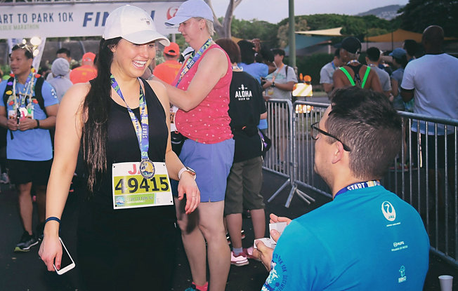 Man proposing to a woman at a marathon finish line
