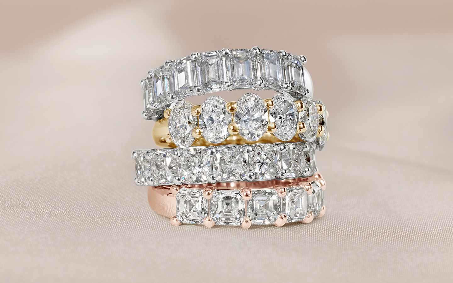 Stack of four wedding rings in rose, yellow, and white gold with brilliant and step-cut diamonds. 
