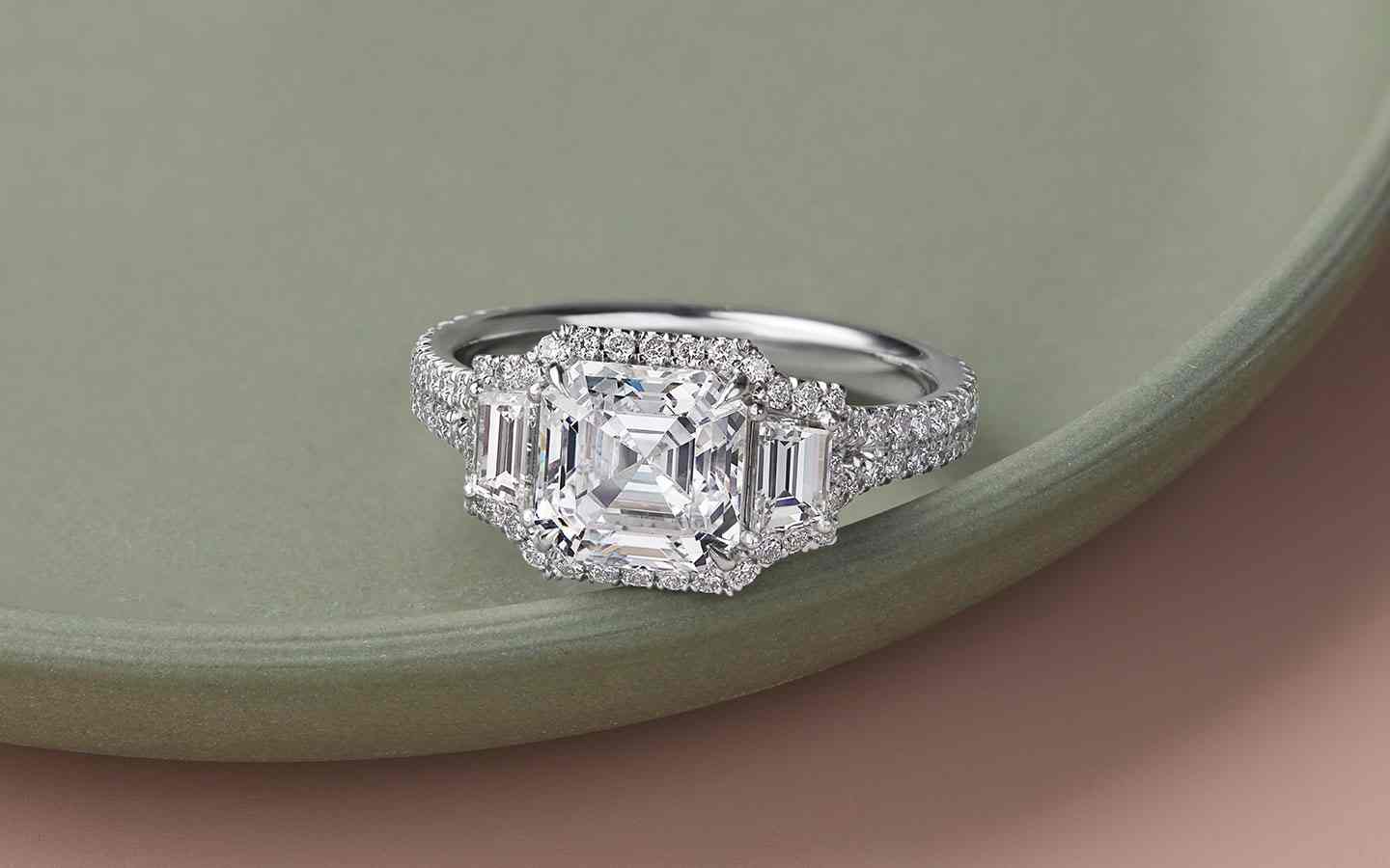 Three-stone engagement ring with center Asscher diamond in 14k white gold. 