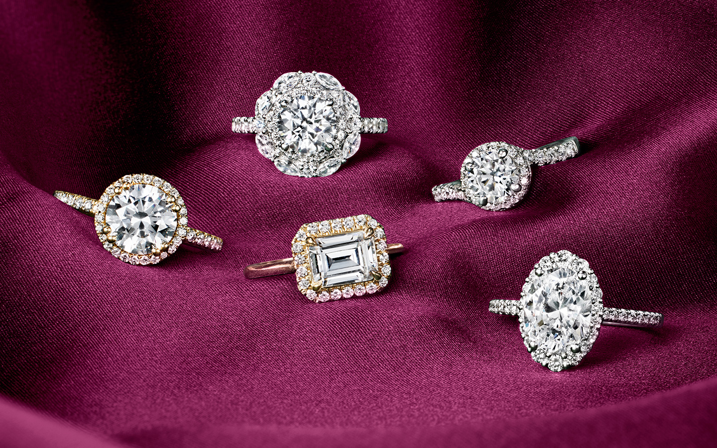 Five diamond and gold engagement rings with round, emerald and oval diamonds.