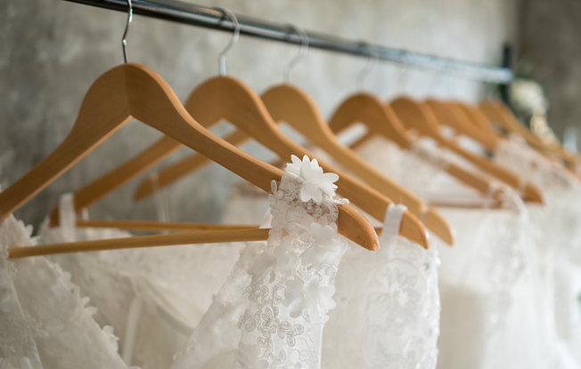 White Wedding dresses on wooden hangers line a rack