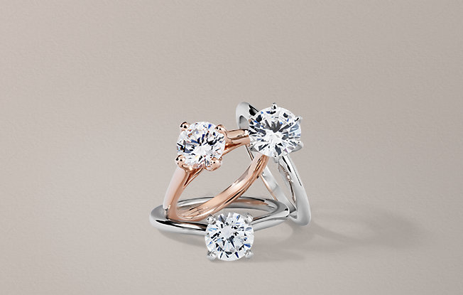Three round solitaire engagement rings in different metals