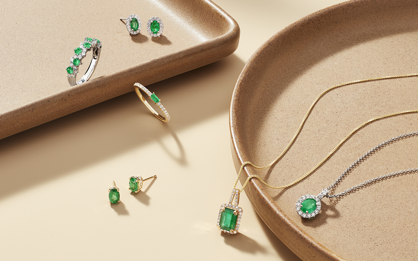 Emerald jewelry displayed on ceramic trays.