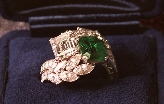 A diamond and emerald engagement ring in a blue velvet box