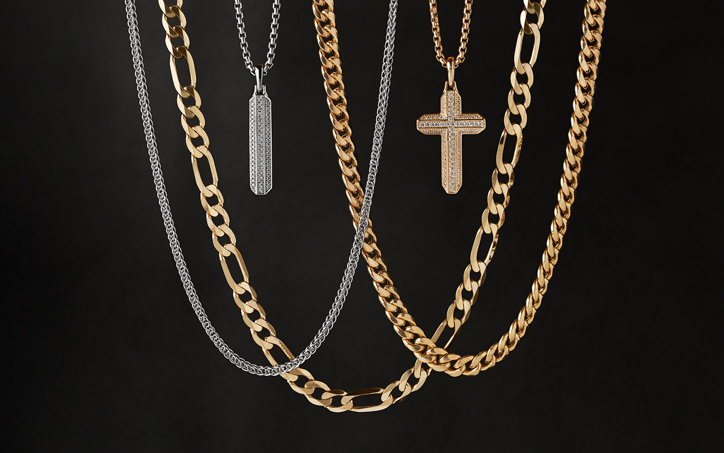 Men’s gold chain necklaces and cross necklaces on a dark background. 