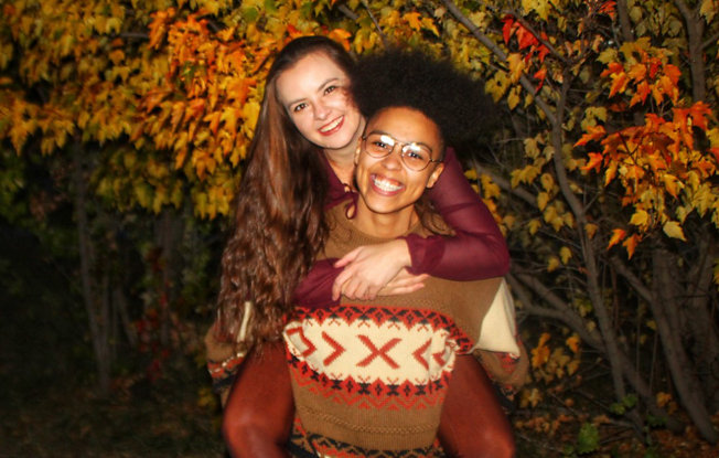 An LGBTQIA+ couple's engagement shoot in the woods surrounded by autumn leaves