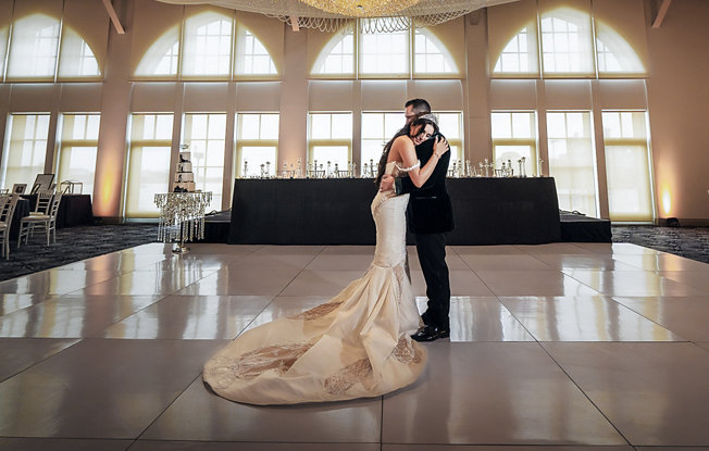 A bride and groom embrace on an elegant dance floor