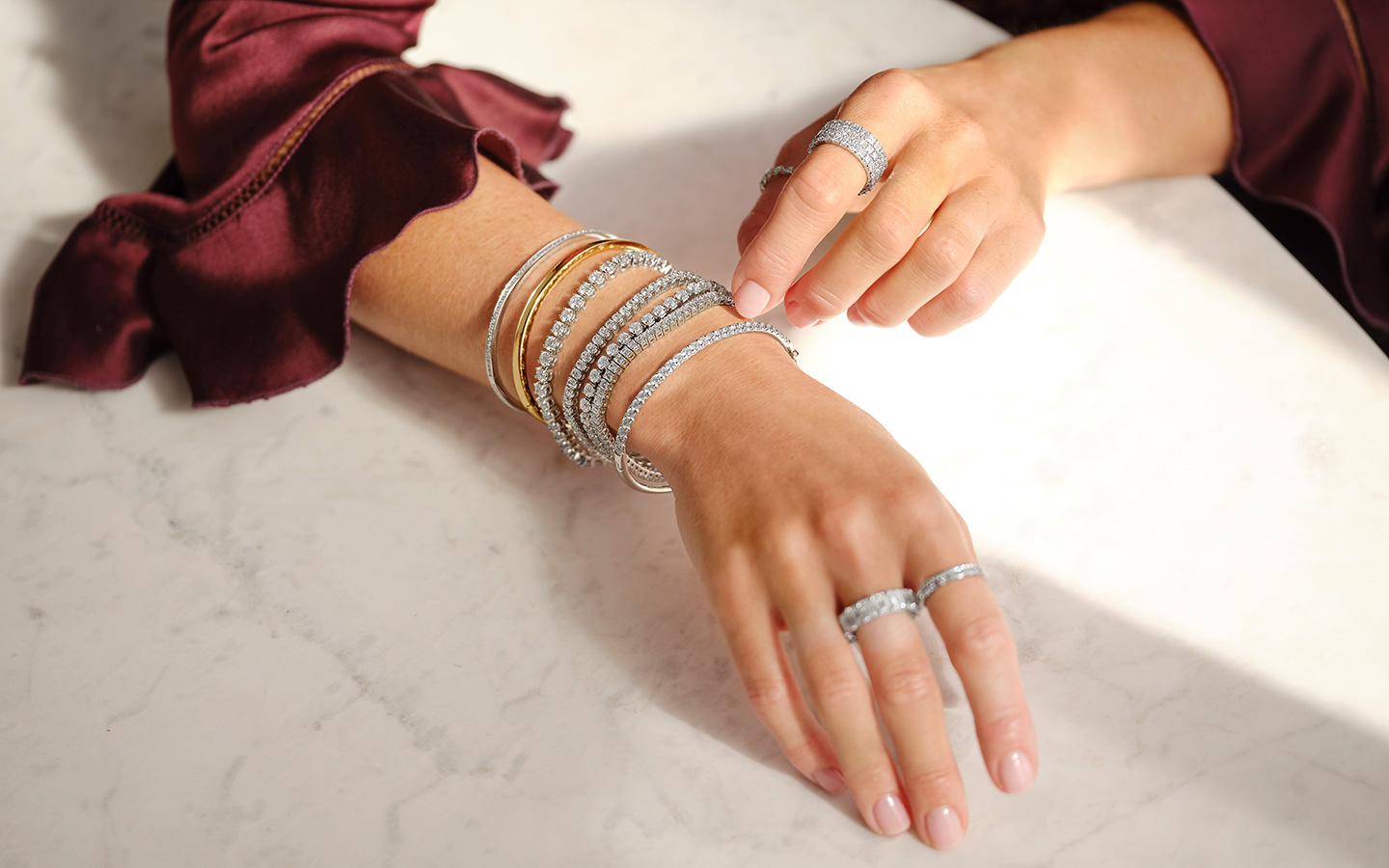 Photo of woman’s arms, she is wearing mixed metal jewelry.