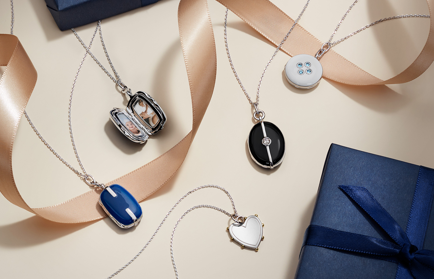 Five gold and silver lockets next to gift boxes.