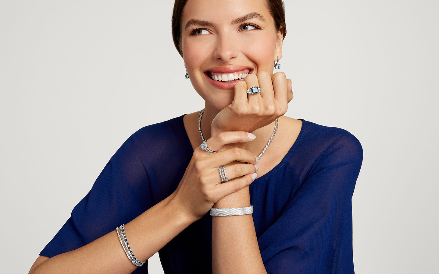 Woman smiling in Blue Nile jewelry, she is wearing two diamond eternity bands together on her right ring finger.
