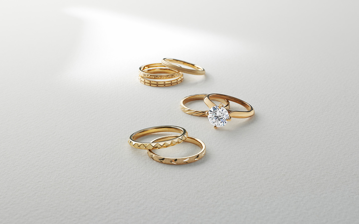 Engagement ring with yellow gold spacer rings of varying textures and designs.
