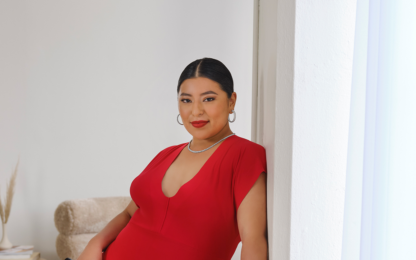 Woman in a red dress wearing statement earrings and a diamond necklace.