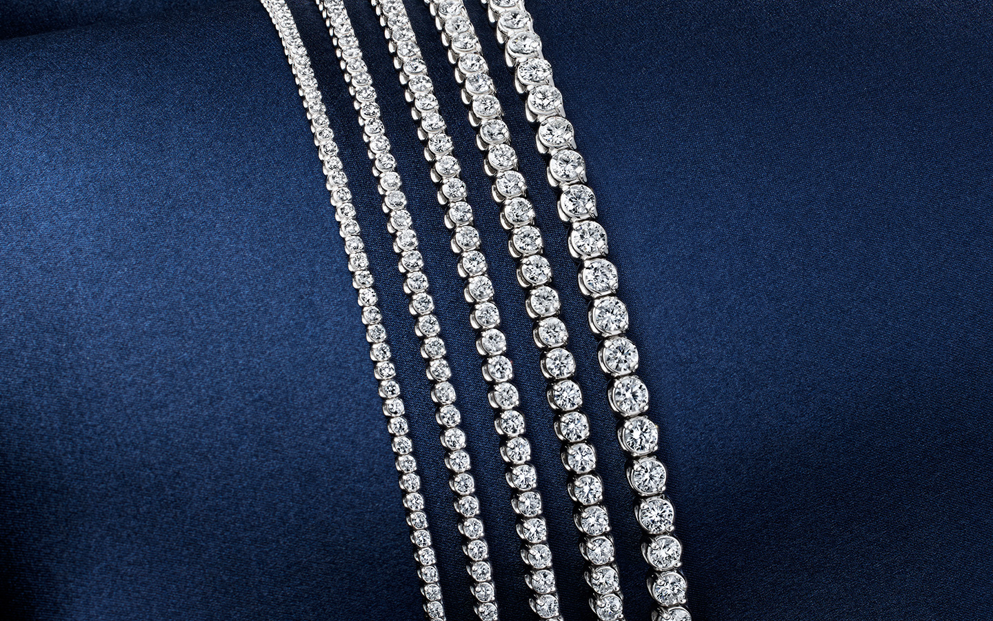 Five tennis bracelets in varying carat weights.