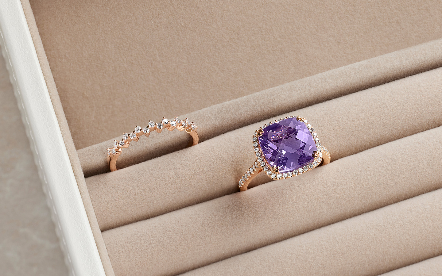 Amethyst and diamond ring displayed alongside a diamond band in a ring storage case.