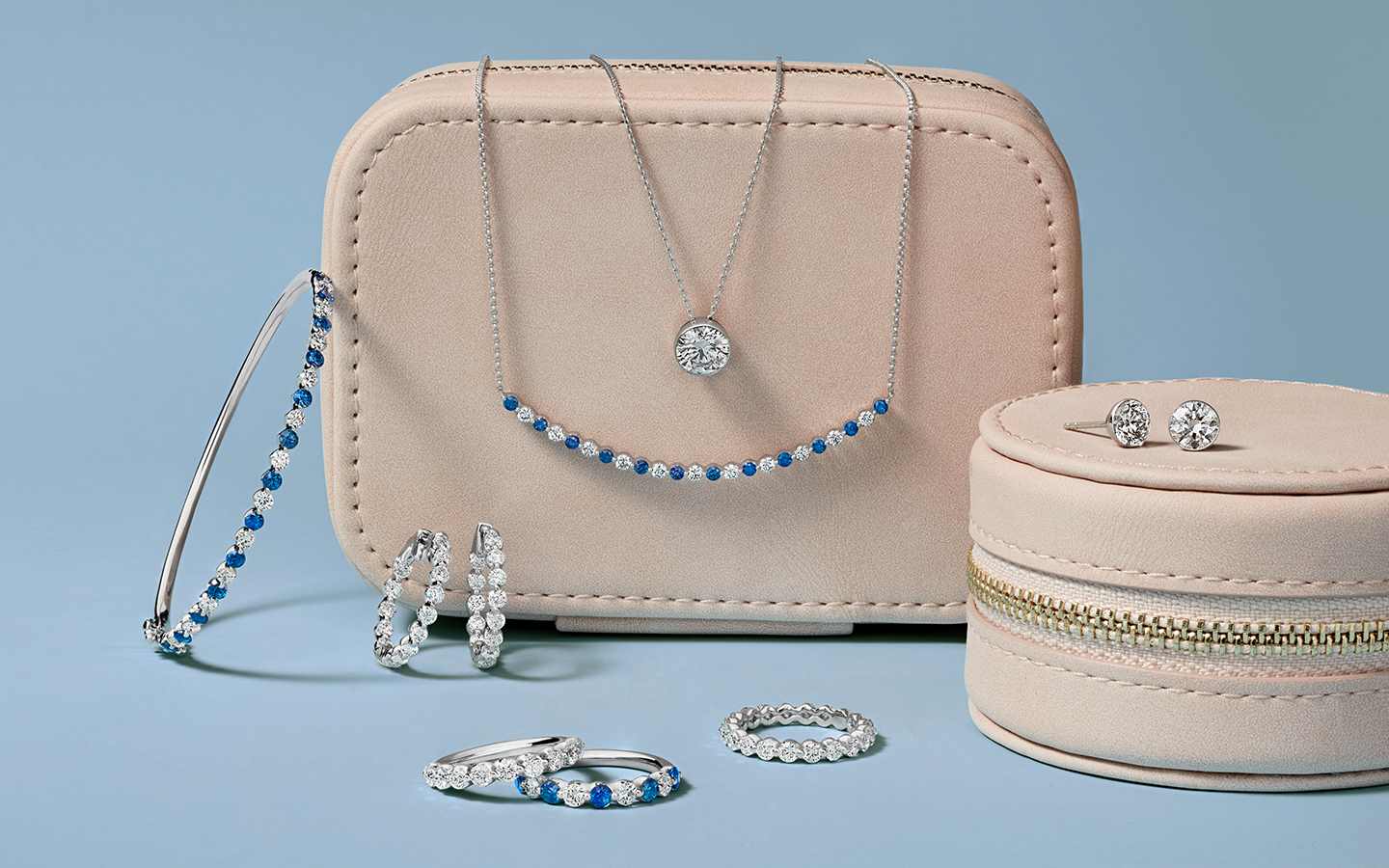 Diamond and sapphire jewelry in white gold displayed on travel jewelry boxes.