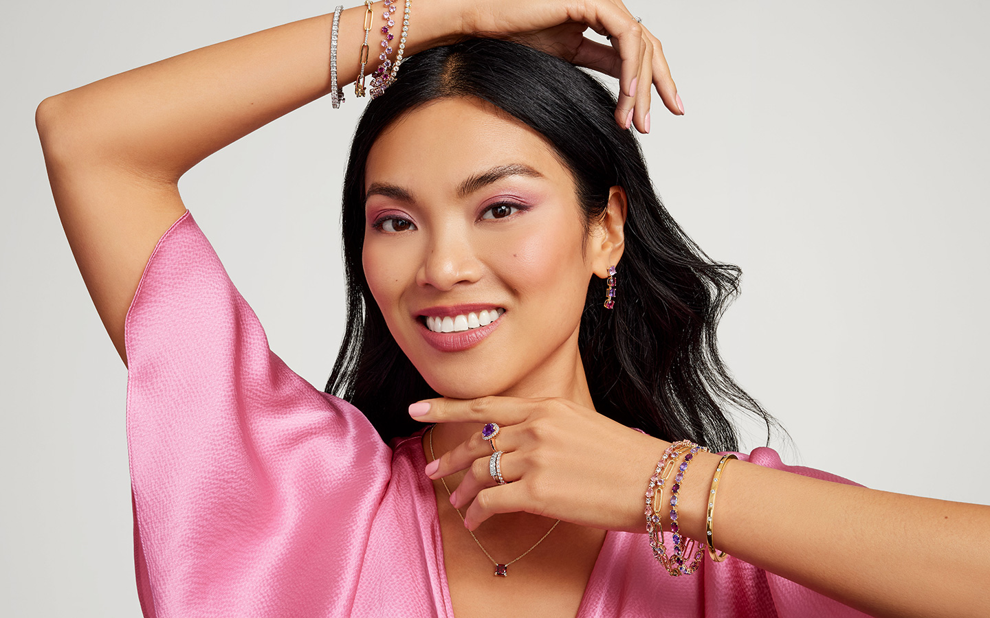 Woman smiling in gemstone Blue Nile jewelry. 