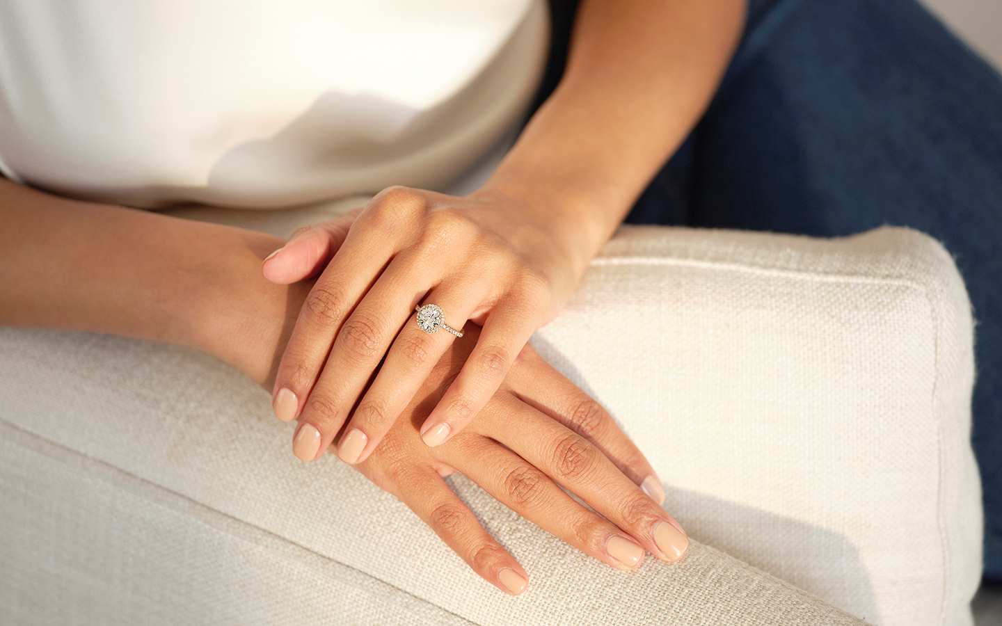 Photo of woman’s hands, she is wearing a warm diamond engagement ring.