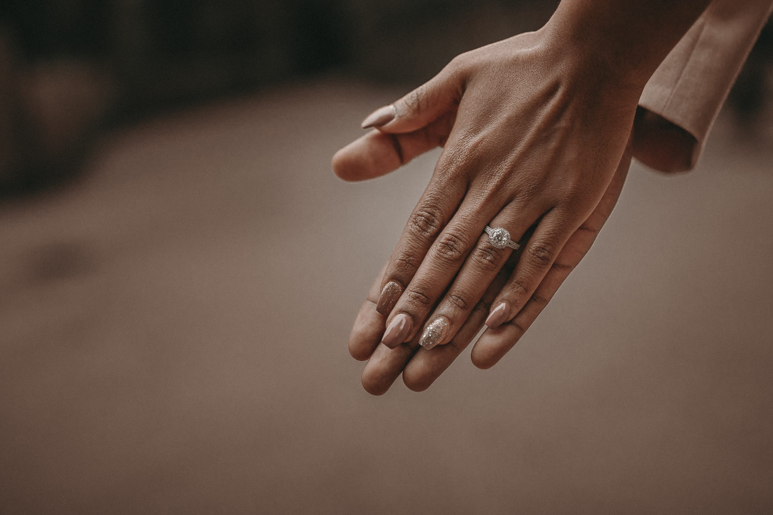 Photo of a bride’s hand pressed up on her groom’s hand. 