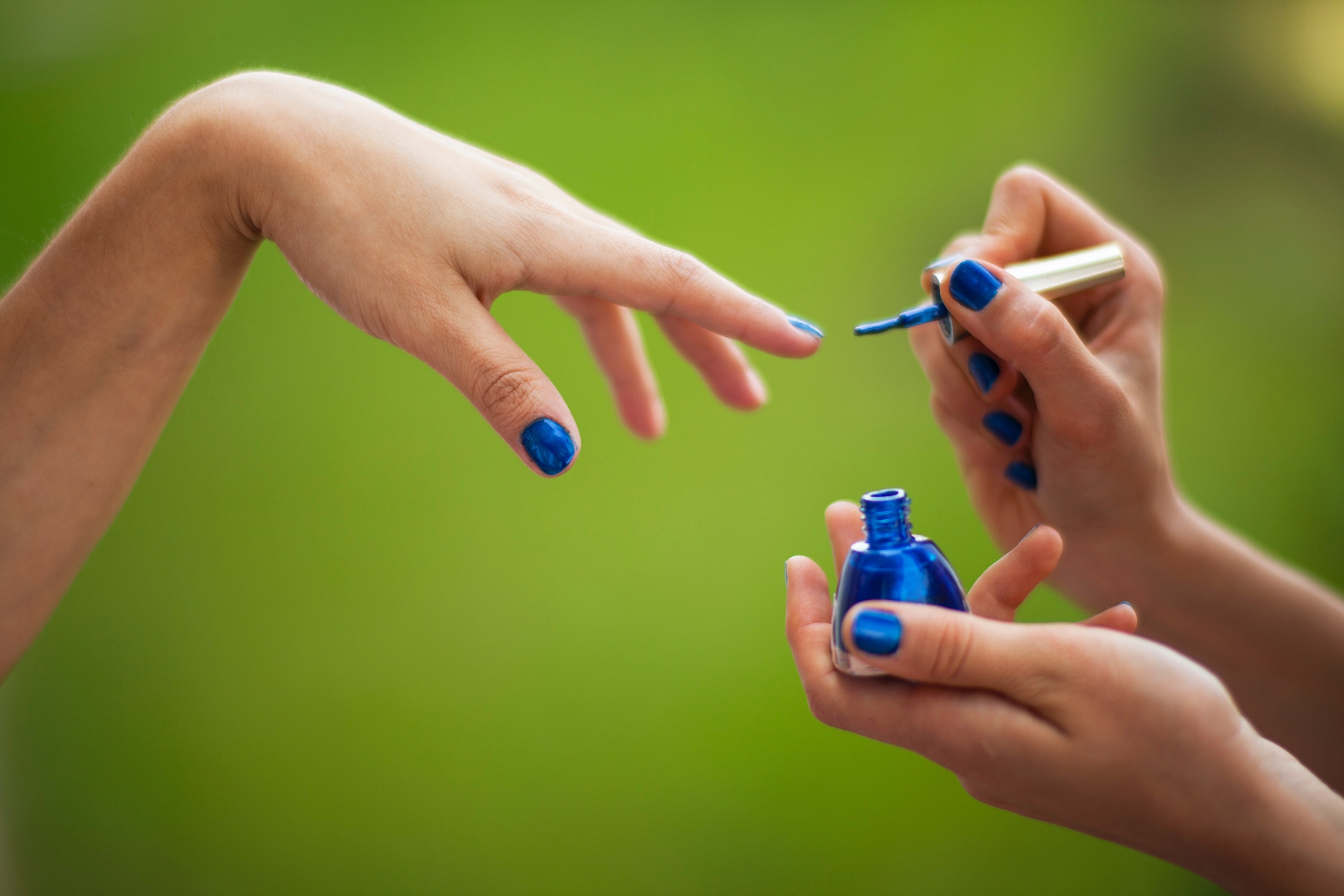 Photo of a person having their nails painted blue. 