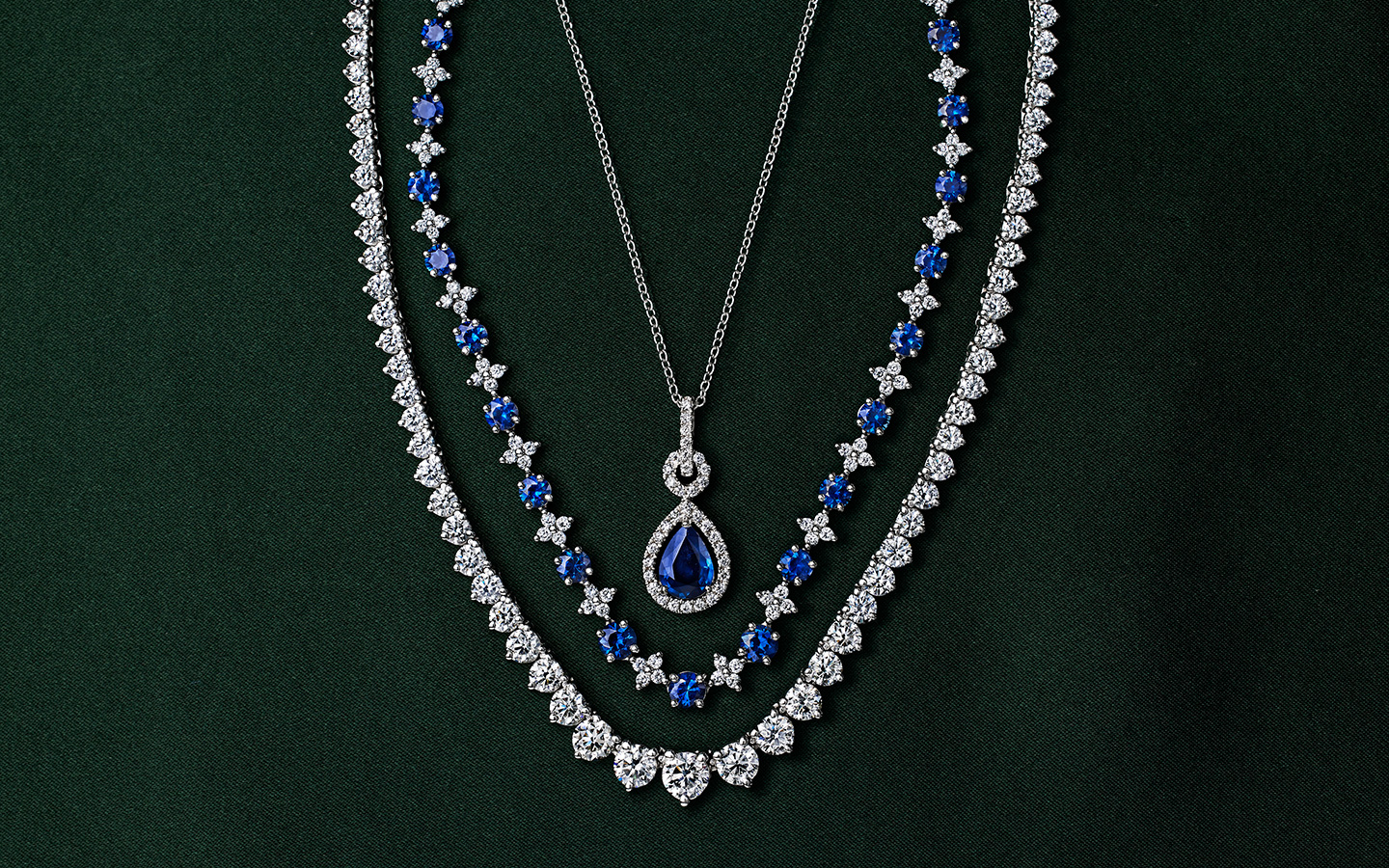 Three white gold necklaces draped together with sapphires and diamonds.