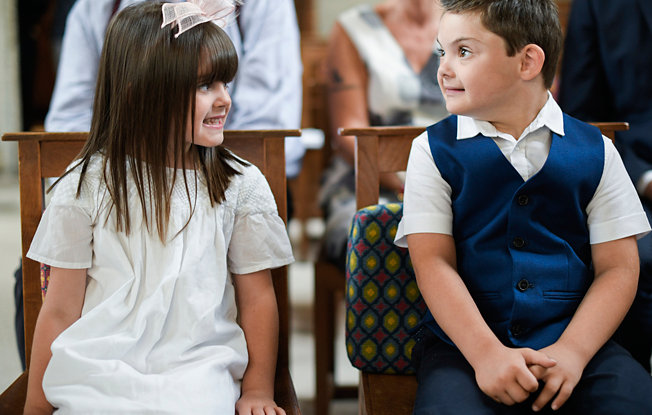 A little boy and girl sit on a bench at a wedding