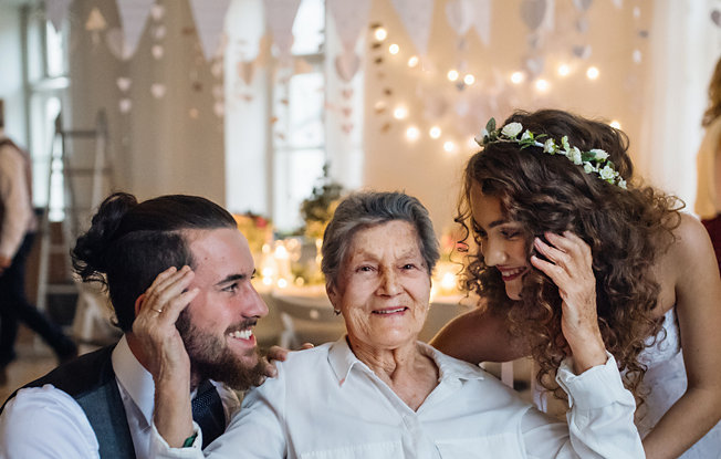 An older woman sat between a bride and groom at their wedding