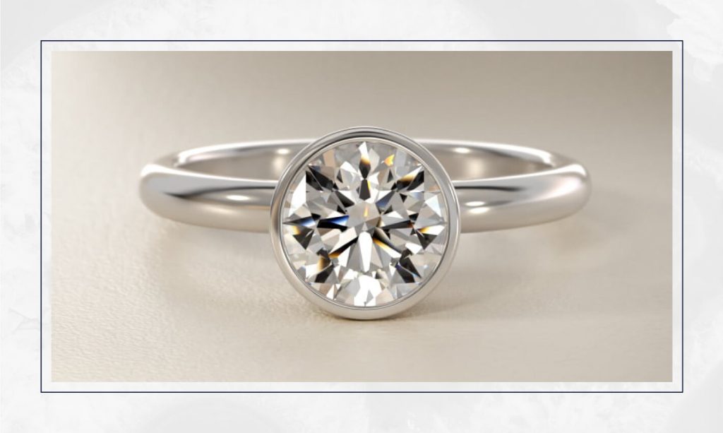 White gold ring with a round diamond secured in a smooth bezel, offering a sleek and modern look seen in trending engagement rings
