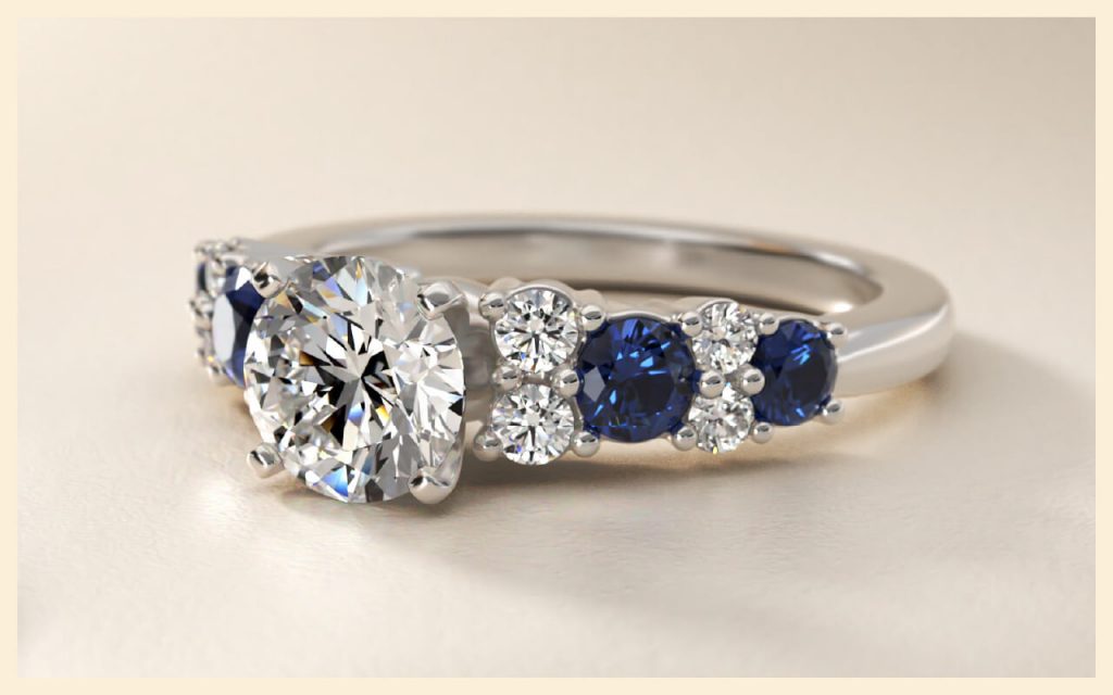 Round diamond paired with deep blue sapphires in a white gold band, a classic option for alternative stones for engagement rings
