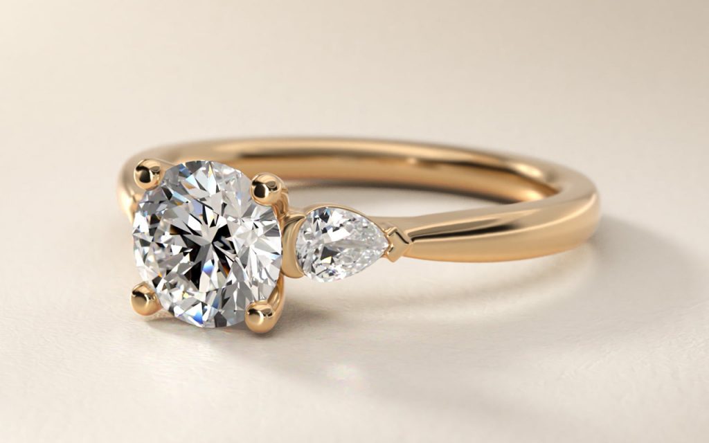 Pear sidestone diamond engagement ring in 14k yellow gold with a round center diamond and pear-shaped accent stone